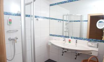 A modern bathroom with a shower and a sink. White tiles and a cozy atmosphere.