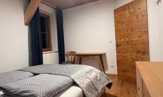 A cozy bedroom with a double bed and a wooden wardrobe. The walls are in light colors and the room has a guest atmosphere.