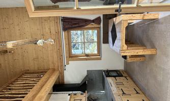 A cozy wooden kitchen with modern appliances and a solid wood dining area. The large window offers a beautiful view outside.