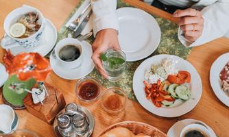 A table set with various dishes and drinks. In the foreground, you can see fresh vegetables and aromatic dips, as well as a cup of coffee.