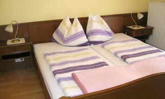 A cozy bedroom with a double bed and colorful pillows. Next to the bed are two nightstands with lamps.