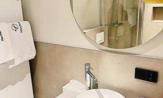 The stylish bathroom of our "Executive" double room has been fully modernized and features an elegant design in warm natural tones. High-quality fixtures, a spacious shower, and a sleek washbasin provide maximum comfort and a relaxing atmosphere.
