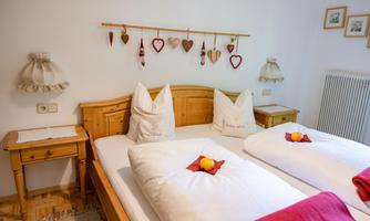 A cozy bedroom with two beds and wooden decor. The walls are adorned with charming ornaments.