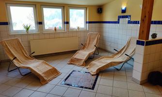A quiet room with two loungers and large windows. The walls are light, and the atmosphere is relaxing.