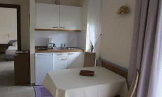 A small, bright kitchen corner with a table and chairs. The kitchen is simply furnished and well equipped.