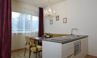 A cozy kitchen with a dining area and elegant chairs. A lovely crystal light hangs above the table, creating an inviting atmosphere.