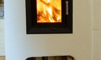 A modern fireplace with a roaring fire. Below it lies a stack of wood.