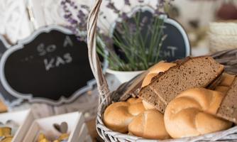 A basket with fresh bread and rolls. In the background, lavender and small signs are visible.