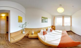 A modern bedroom with a large bed and wooden details. The room is bright and welcoming with windows that allow natural light in.