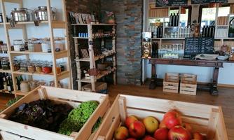 A lovingly decorated grocery store with wooden crates full of fresh apples and lettuce. In the background, there are shelves with various products and a large table.