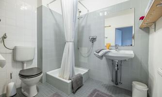 A modern bathroom equipped with a shower, sink, and toilet. The walls are painted in light gray tones and there is a large mirror.