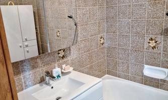 A modern bathroom with a bathtub and a sink. The walls are designed with tiled, decorative patterns.