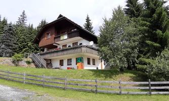 A charming house surrounded by green trees and meadows. The architecture is typical of the alpine region.