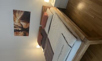 A cozy bedroom with a double bed and soft lights. A picture of a tree in autumn hangs on the wall.