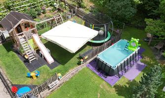 A beautiful garden with play areas for children. There is a slide, a trampoline, and a swimming pool.