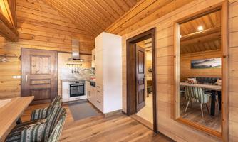 A cozy wooden cabin with a modern interior. The kitchen and dining area are well designed and inviting.