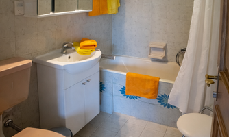 A small bathroom with a bathtub and a sink. Colorful towels and floral patterns give the space a fresh look.