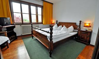 A cozy bedroom with a large wooden bed and bright curtains. The room is well-lit and has a warm, inviting look.
