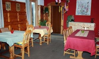 A cozy room with wood paneling and several tables. The walls are painted red, and there are decorative plants as well as a piece of artwork.