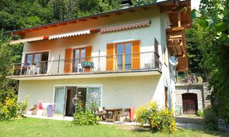 A cozy house with orange shutters and a balcony. The garden is green and blooming, perfect for relaxing.