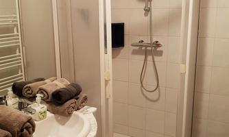 A modern bathroom with a shower cubicle and a sink unit. Clean towels and an elegant tile pattern complement the space.