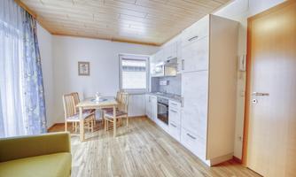 A modern kitchen with a dining area and a cozy sofa. The room is bright and friendly designed.