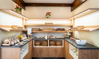 A cozy kitchen with wooden shelves and a table decorated with various baked goods and snacks. Below are also bowls and jars for the presentation of the food.