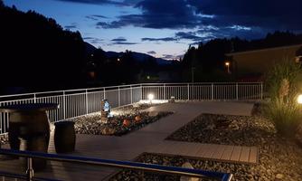 A quiet terrace at night with soft lighting. In the background are mountains and the sky is partially cloudy.