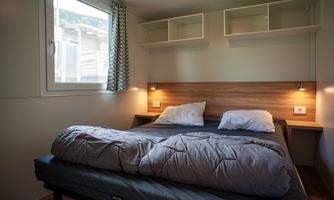 A cozy bedroom with a double bed and soft lighting. The window lets in natural light, creating an inviting atmosphere.