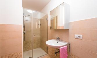 A modern bathroom with a shower niche and a sink. The walls are in soft beige and cream tones.
