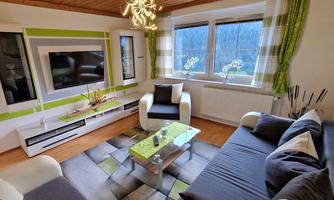A modern living room with a cozy sofa and a glass table. Large windows let in plenty of light, and the walls are painted in fresh colors.