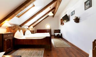 A cozy bedroom with a wooden bed and slanted walls. The decor is simple and inviting, with a window that lets in plenty of light.