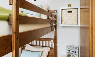 A cozy children's room with a bunk bed and a bright, friendly atmosphere. On the wall are decorative eyes and a shelf with storage boxes.