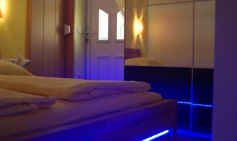 A modern bedroom with a comfortable bed and indirect lighting. The walls are in warm yellow tones and there is a mirror that enlarges the space.