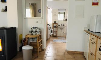 A cozy room with a kitchenette and a view of a bathroom. An oven and a chair create an inviting atmosphere.