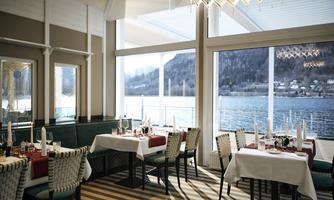 An elegant restaurant with a view of the lake. The tables are stylishly set and decorated with attractive details.