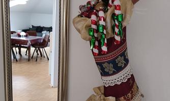 A decorative Christmas stocking hangs on the wall. In the background, a dining area with a table and chairs can be seen.