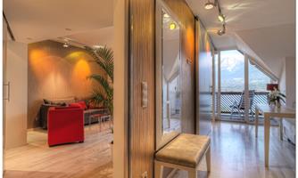 A modern living room with a red sofa and a large window. The space is bright and welcoming, with wooden floors and a cozy atmosphere.