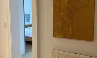 A bright hallway with a golden mural. In the background, a bedroom can be seen.