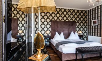 An elegant bedroom with a large double bed and elegant decoration. A stylish lamp stands on a black table next to the bed.