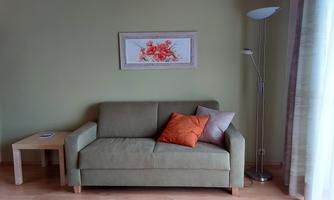 A modern living room with a bright green color scheme. A comfortable sofa with cushions and a side table are clearly visible.