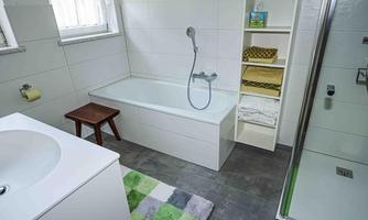 A modern bathroom with a bathtub and a shower cubicle.  
Bright colors and a pleasant atmosphere create an inviting space.