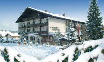 A beautiful hotel in the snow with a clear blue sky.  
Surrounded by snowy trees and an inviting atmosphere.