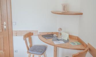 A bright room with a small desk and two chairs. On the table are books and writing materials.