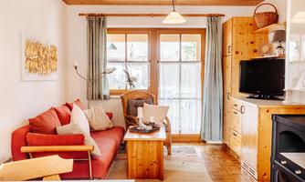 A cozy living room with a red sofa and wood paneling. Large windows provide plenty of daylight and an inviting atmosphere.