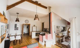 A bright and modern kitchen with wooden beams and an open living area. The furniture is simple and inviting, perfect for cozy evenings.