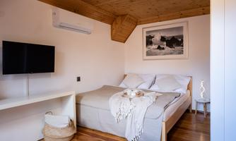 A cozy bedroom with a large bed and a wooden ceiling. There is a television and a decorative lamp on a table.
