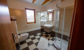 A modern bathroom with a shower, sink, and toilet. The room has bright walls and a checkered pattern floor.