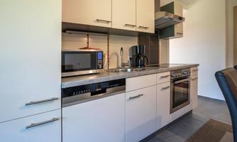 A modern kitchen with bright cabinets and high-quality appliances. The equipment includes a stove, an oven, and a microwave.