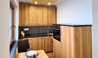 A modern kitchen with wood and black accents. The dining area consists of a small table and two chairs.